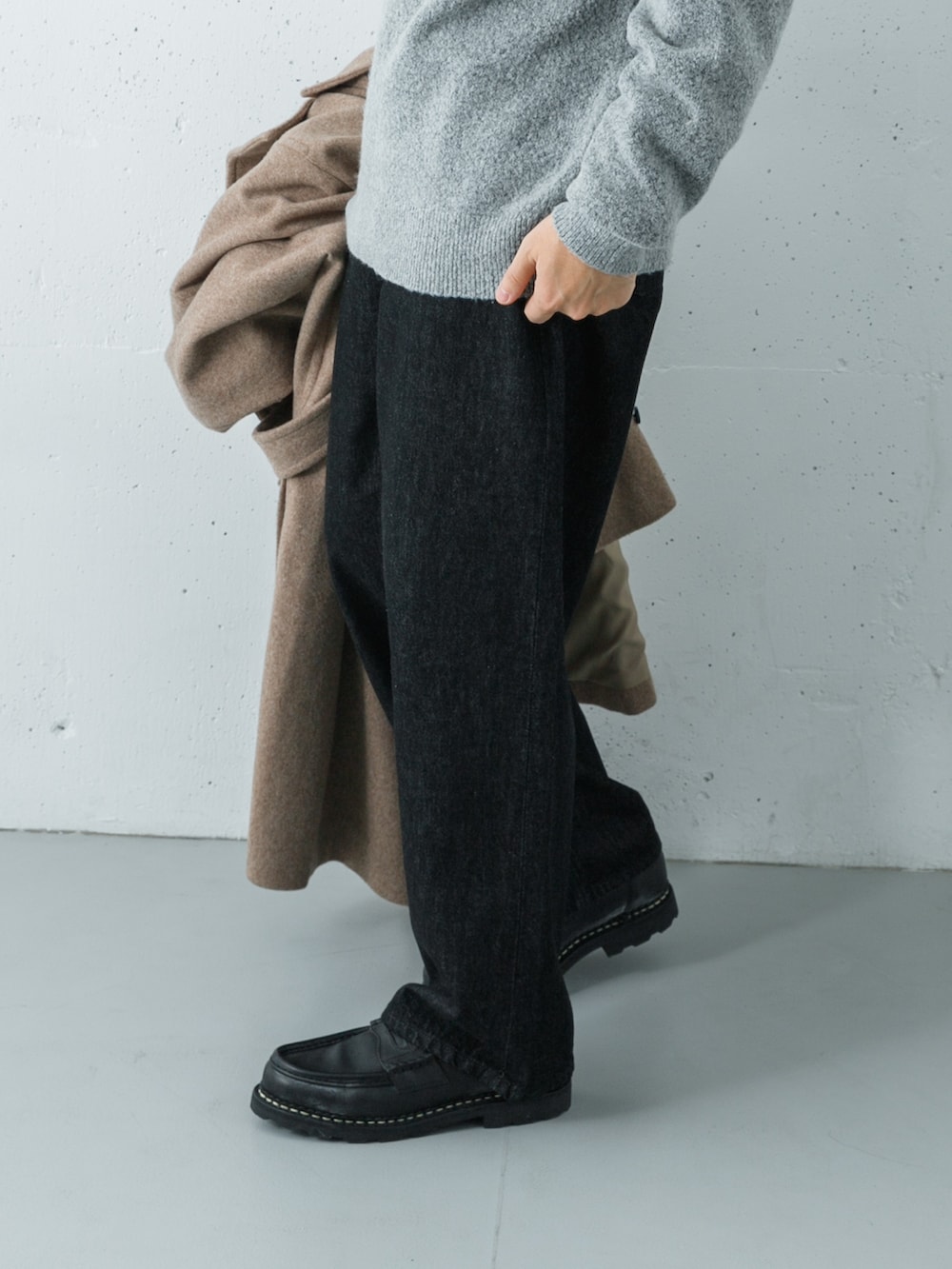 ブラック系のデニムパンツ、ベージュ系のステンカラーコート、グリーン系のニット/セーターを着用したメンズの冬コーディネートの6枚目の写真