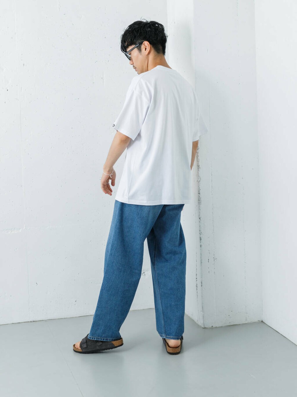 ブルー系のデニムパンツ、グレー系のサンダル、ホワイト系のTシャツ/カットソーを着用したメンズの夏コーディネートの6枚目の写真