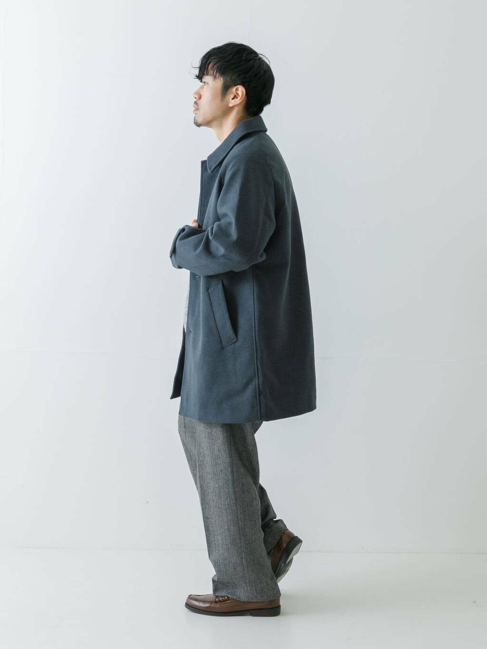 ブルー系のステンカラーコート、グレー系のニット/セーター、グレー系のスラックスを着用したメンズの冬コーディネートの5枚目の写真
