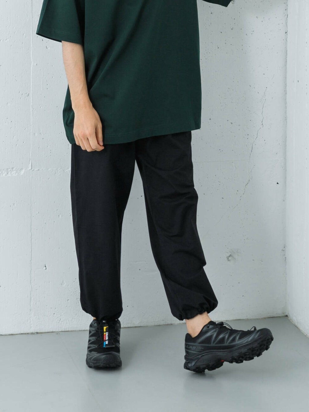 ブラック系のスニーカー、ブルー系のその他パンツ、グリーン系のTシャツ/カットソーを着用したメンズの夏コーディネートの4枚目の写真