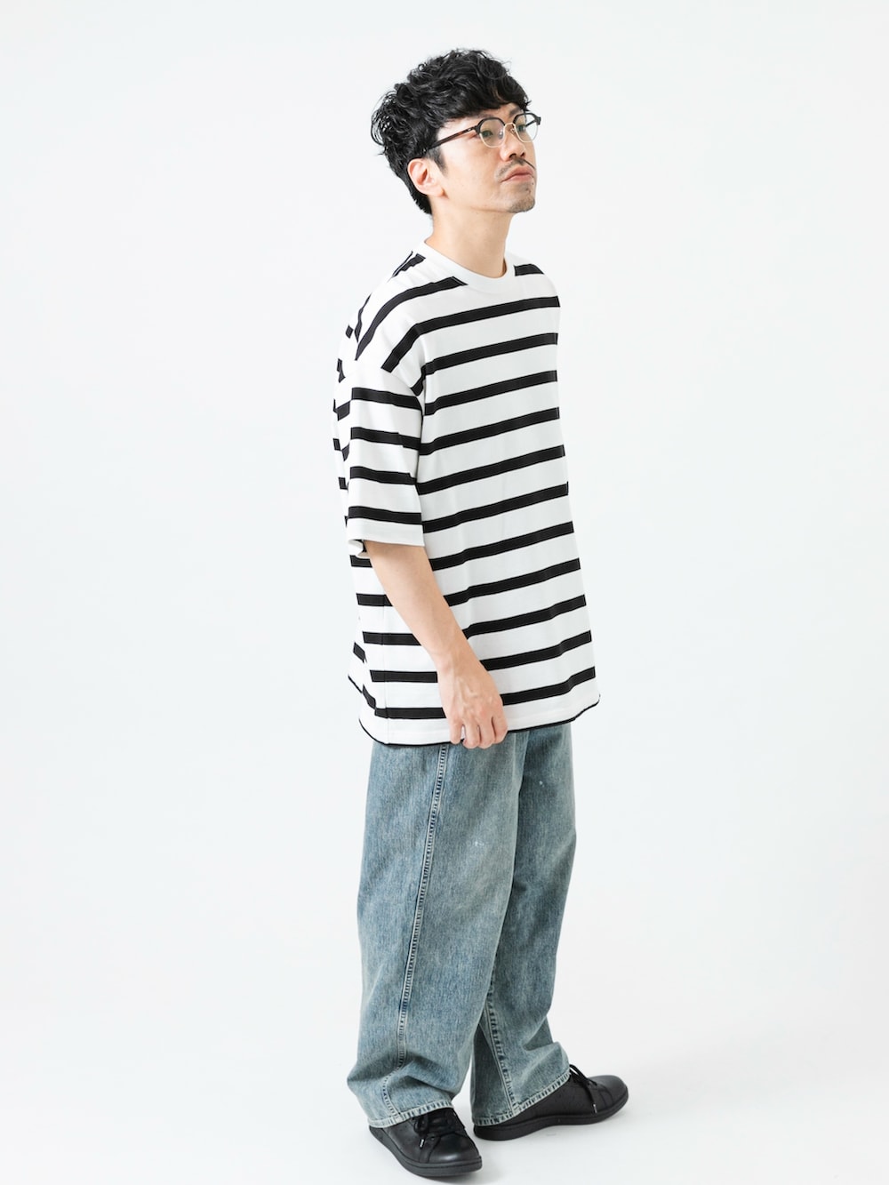 ブラック系のスニーカー、ホワイト系のTシャツ/カットソー、ブルー系のデニムパンツを着用したメンズの夏コーディネートの4枚目の写真