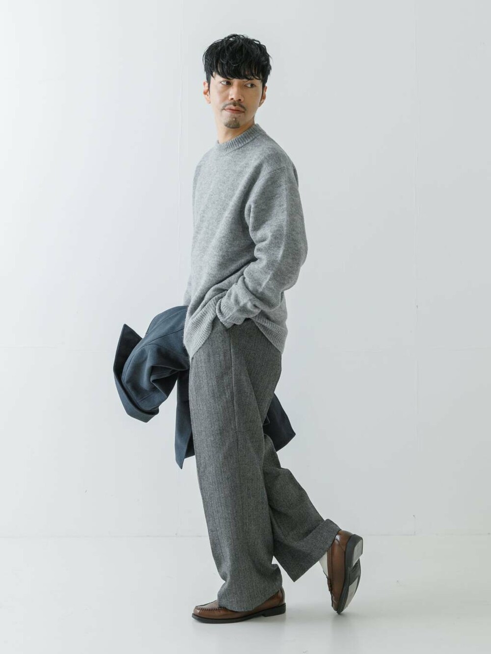ブルー系のステンカラーコート、グレー系のニット/セーター、グレー系のスラックスを着用したメンズの冬コーディネートの7枚目の写真