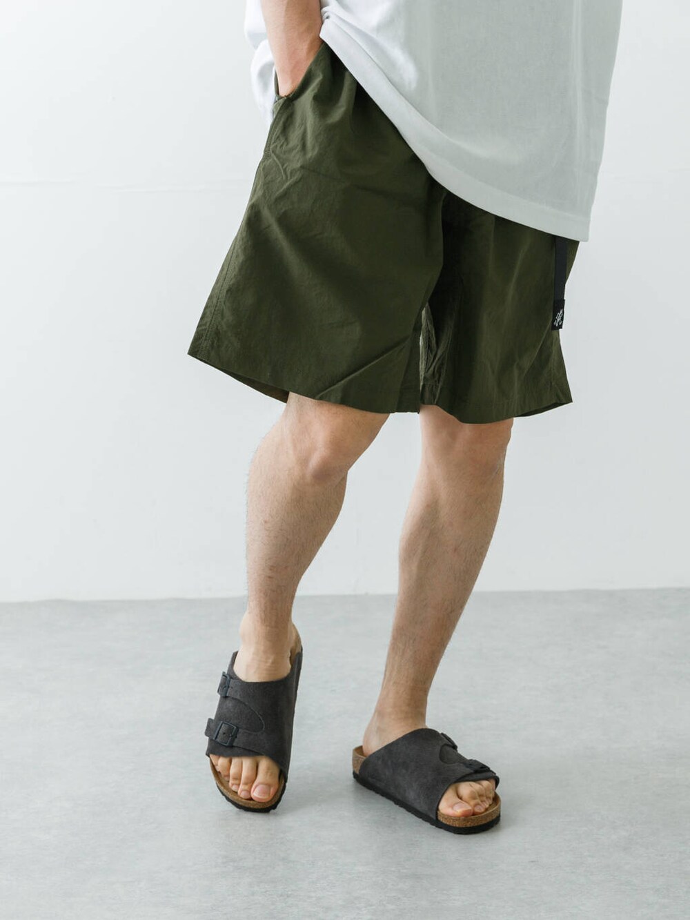 グリーン系のその他パンツ、グレー系のサンダル、ホワイト系のTシャツ/カットソーを着用したメンズの春コーディネートの4枚目の写真