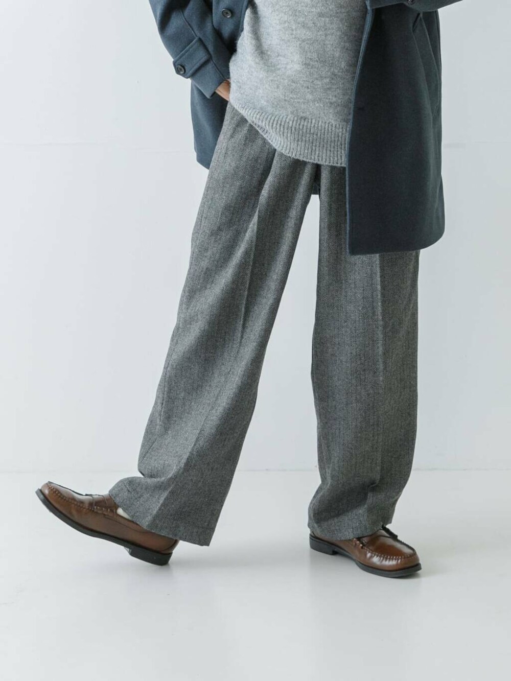 ブルー系のステンカラーコート、グレー系のニット/セーター、グレー系のスラックスを着用したメンズの冬コーディネートの2枚目の写真