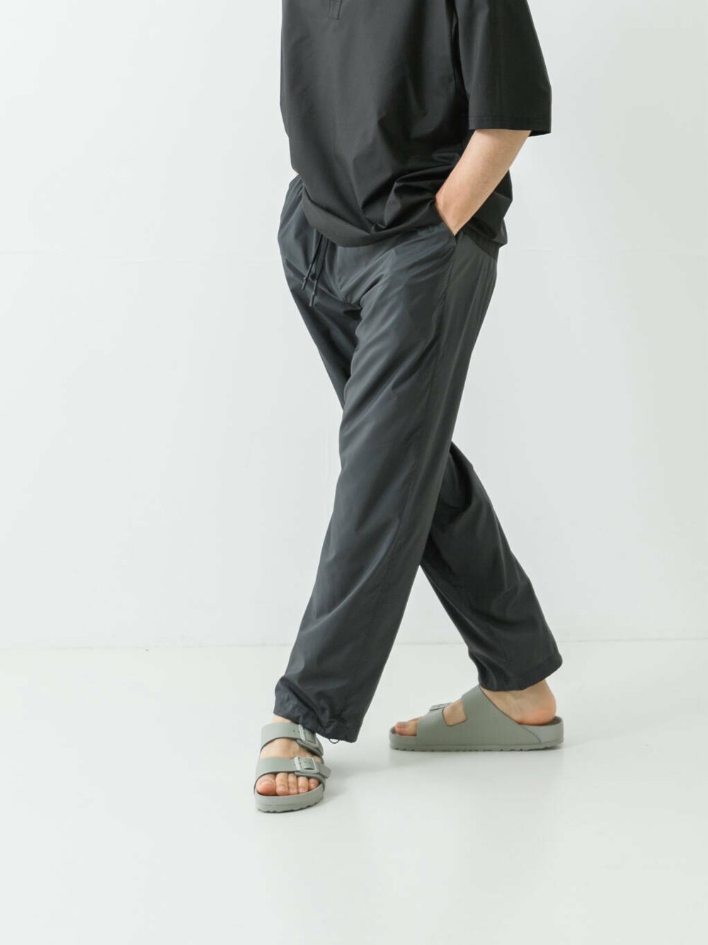 グレー系のサンダル、ブラック系のポロシャツ、グレー系のその他パンツを着用したメンズの夏コーディネートの3枚目の写真