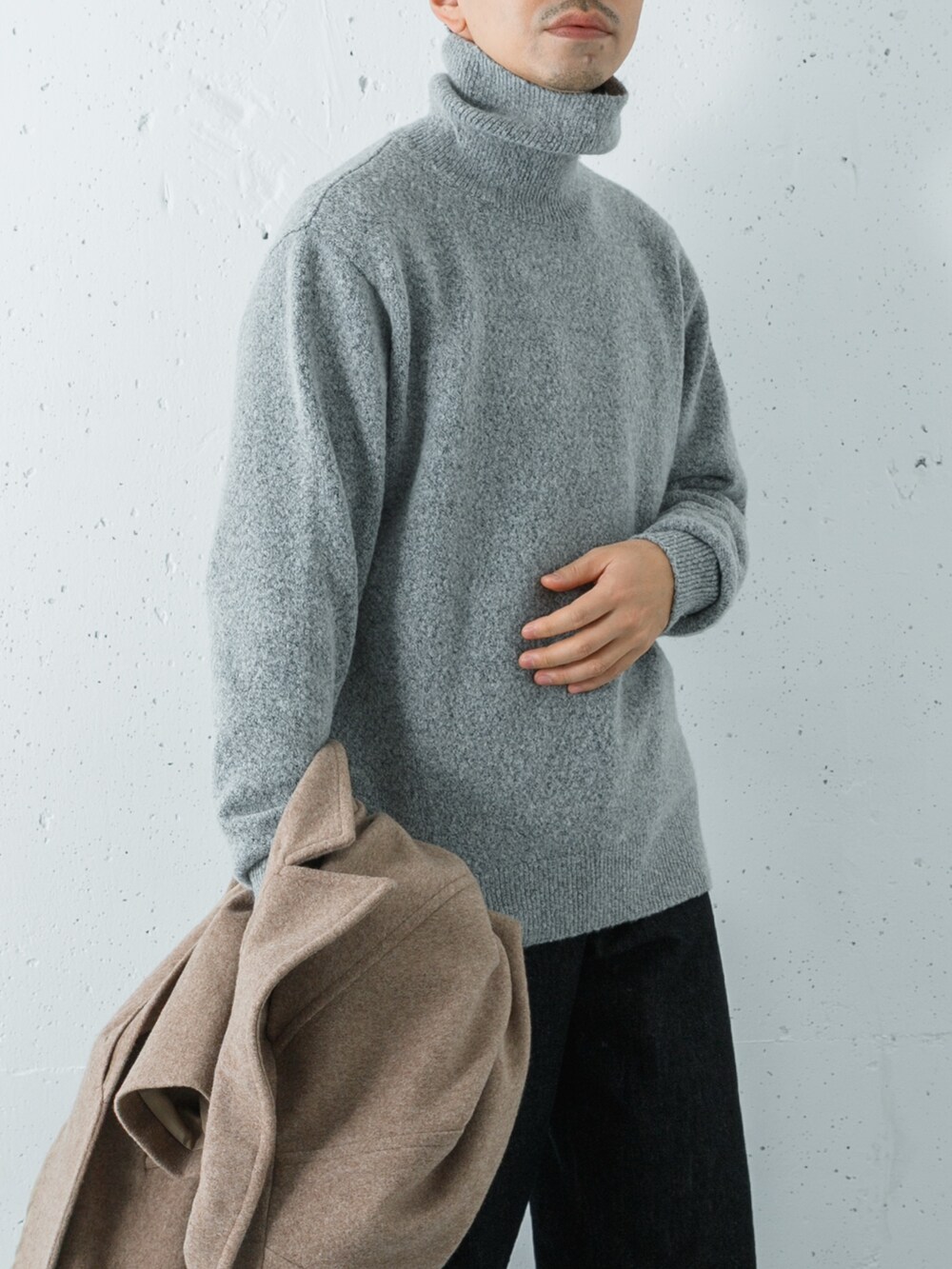 ブラック系のデニムパンツ、ベージュ系のステンカラーコート、グリーン系のニット/セーターを着用したメンズの冬コーディネートの5枚目の写真