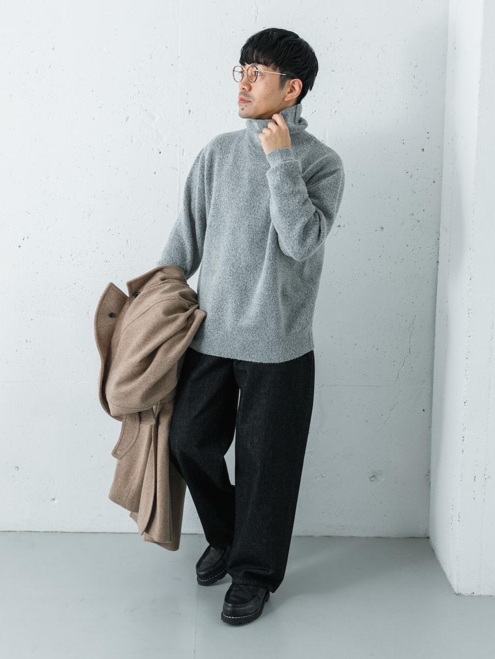 ブラック系のデニムパンツ、ベージュ系のステンカラーコート、グリーン系のニット/セーターを着用したメンズの冬コーディネートの4枚目の写真