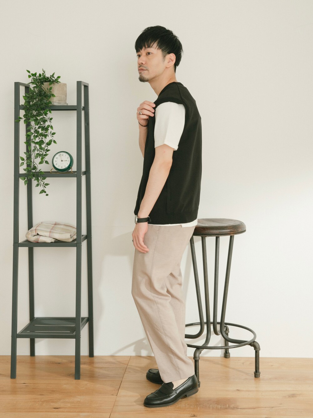 ベージュ系のスラックス、ブラック系のベスト、ホワイト系のその他を着用したメンズの春コーディネートの2枚目の写真