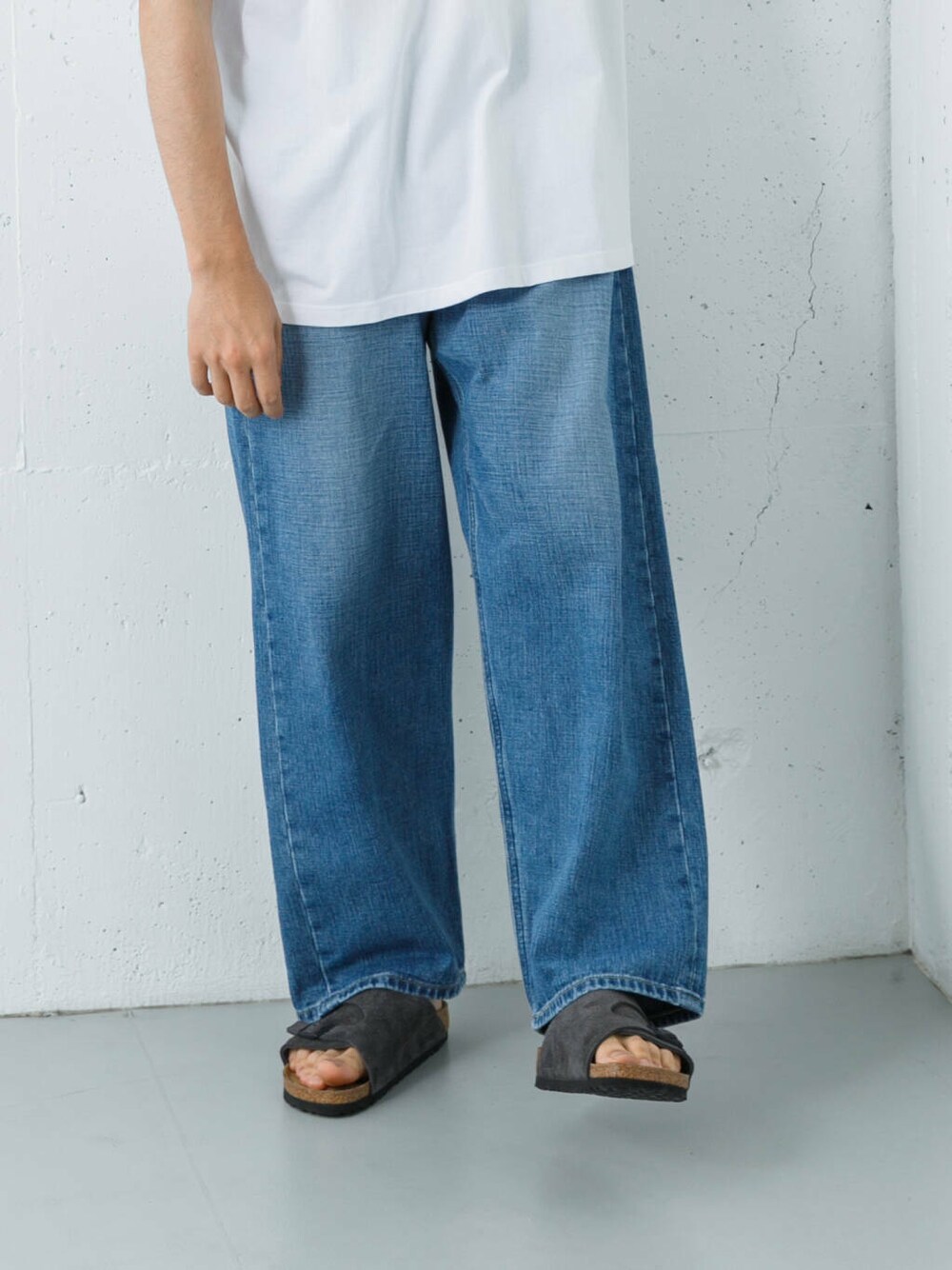 ブルー系のデニムパンツ、グレー系のサンダル、ホワイト系のTシャツ/カットソーを着用したメンズの夏コーディネートの3枚目の写真
