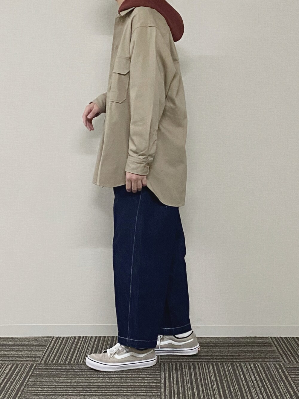 ベージュ系のブルゾン、ブラウン系のパーカー、ブルー系のデニムパンツを着用したメンズの春コーディネートの2枚目の写真