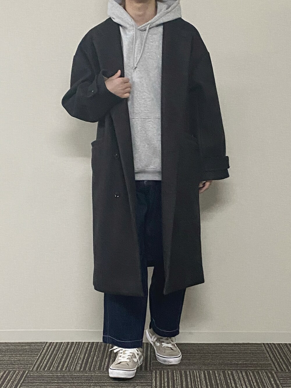 ブラック系のパーカー、グリーン系のチェスターコート、ブルー系のデニムパンツを着用したメンズの冬コーディネートの2枚目の写真