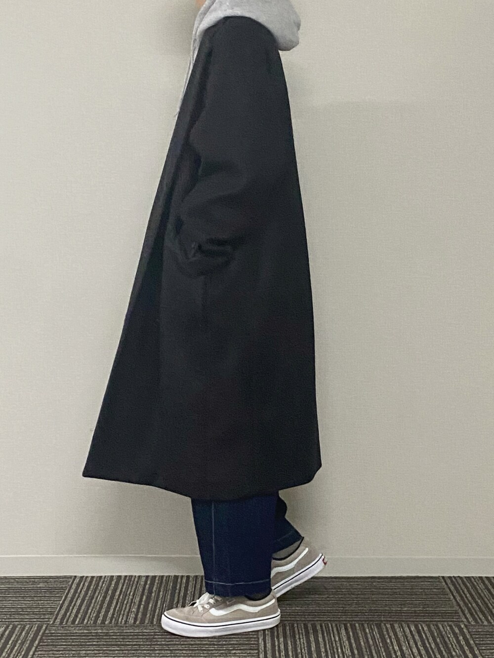 ブラック系のパーカー、グリーン系のチェスターコート、ブルー系のデニムパンツを着用したメンズの冬コーディネートの3枚目の写真