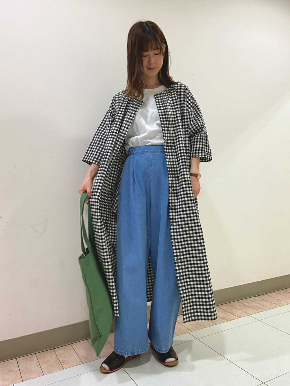 ホワイト系のマウンテンパーカー、ブラック系のワンピース、グリーン系のトートバッグを着用したレディースの春コーディネートの2枚目の写真