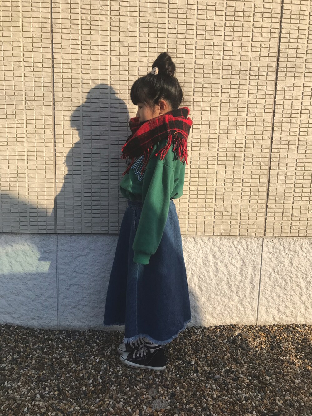 ブルー系のデニムスカート、グリーン系のTシャツ/カットソー、レッド系のストール/ショールを着用したキッズの冬コーディネートの2枚目の写真