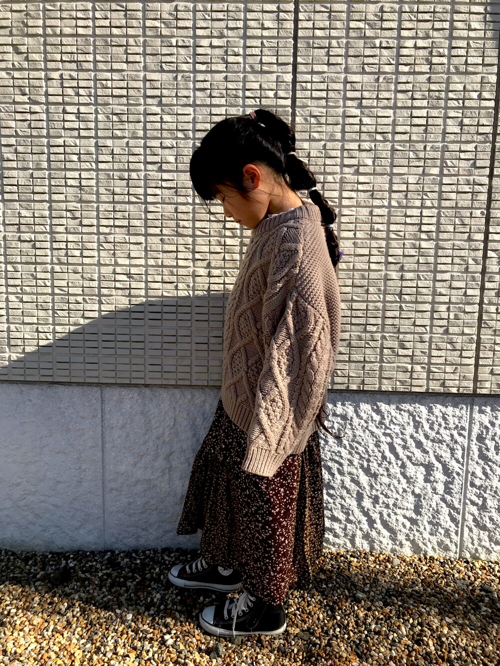 ベージュ系のニット/セーター、ブラウン系のスカートを着用したキッズの冬コーディネートの2枚目の写真