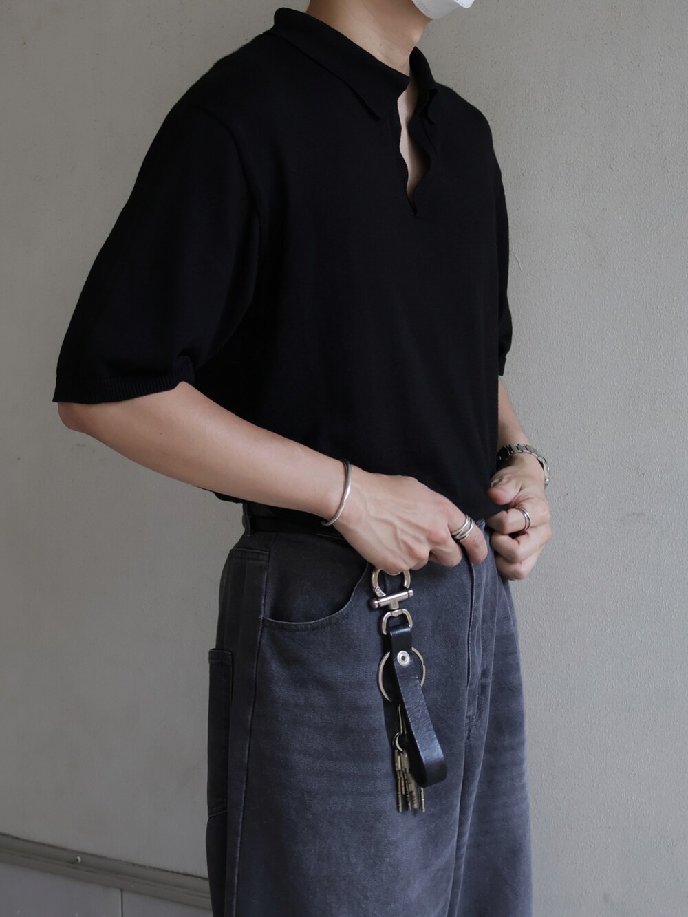 ブラック系のポロシャツ、グレー系のスラックスを着用したメンズの夏コーディネートの3枚目の写真