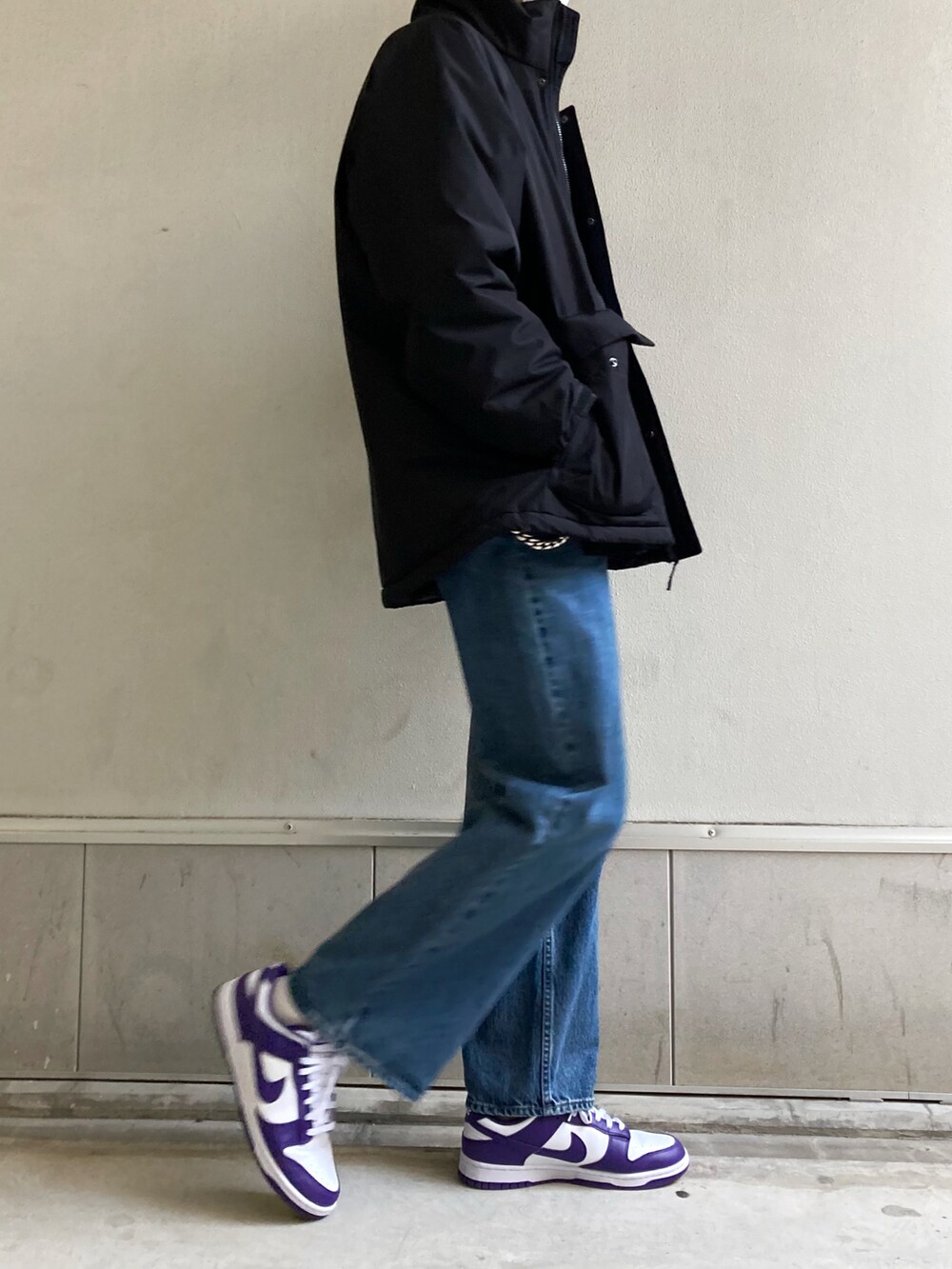 グレー系のTシャツ/カットソー、ブラック系のダウンジャケット/コート、ブルー系のデニムパンツを着用したメンズの春コーディネートの2枚目の写真