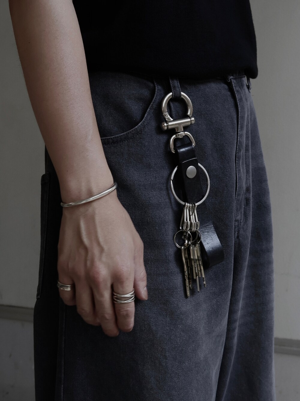 ブラック系のポロシャツ、グレー系のスラックスを着用したメンズの夏コーディネートの2枚目の写真