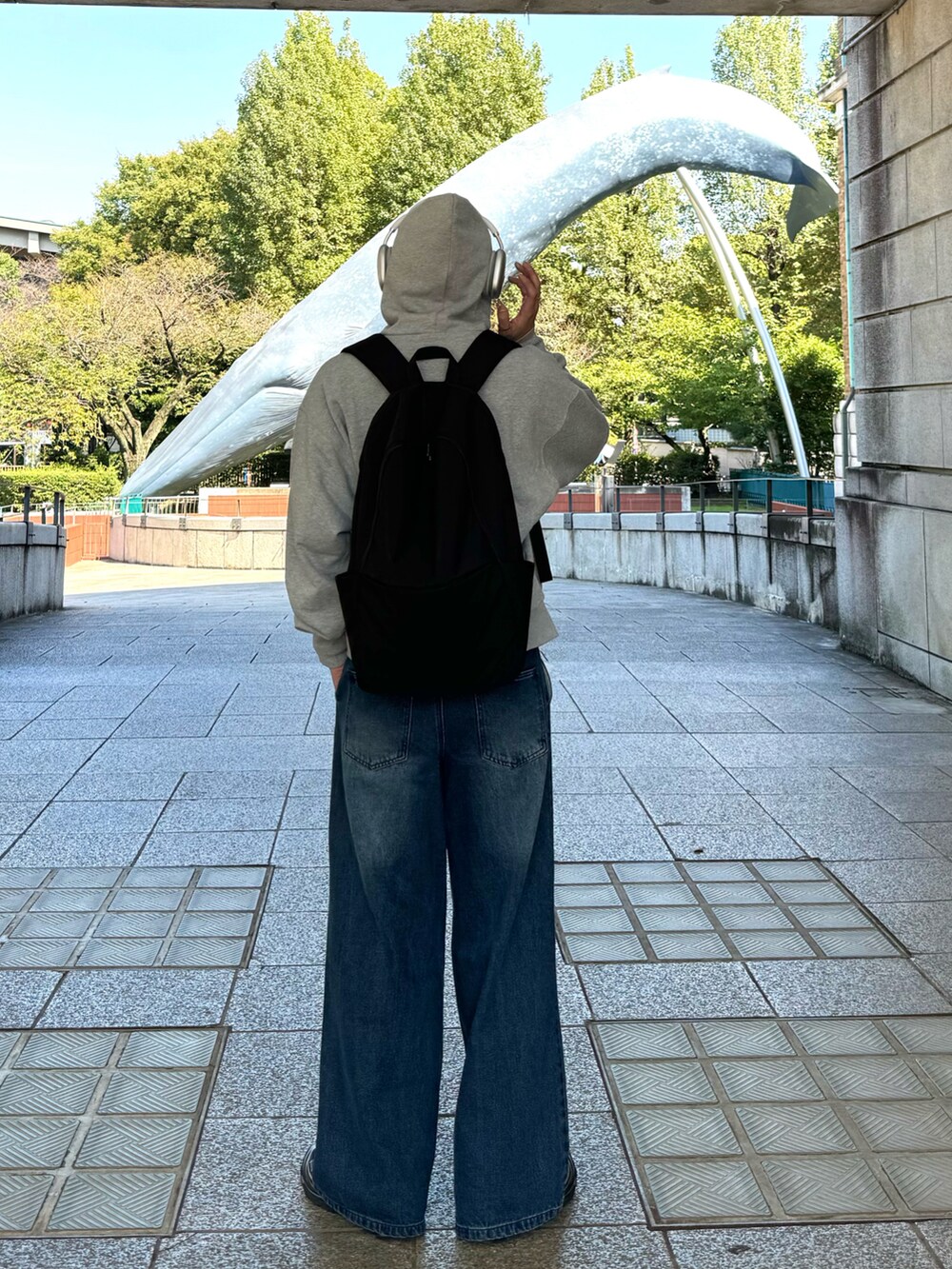 グレー系のパーカー、ブラック系のバックパック/リュック、ブルー系のデニムパンツを着用したメンズの秋コーディネートの2枚目の写真