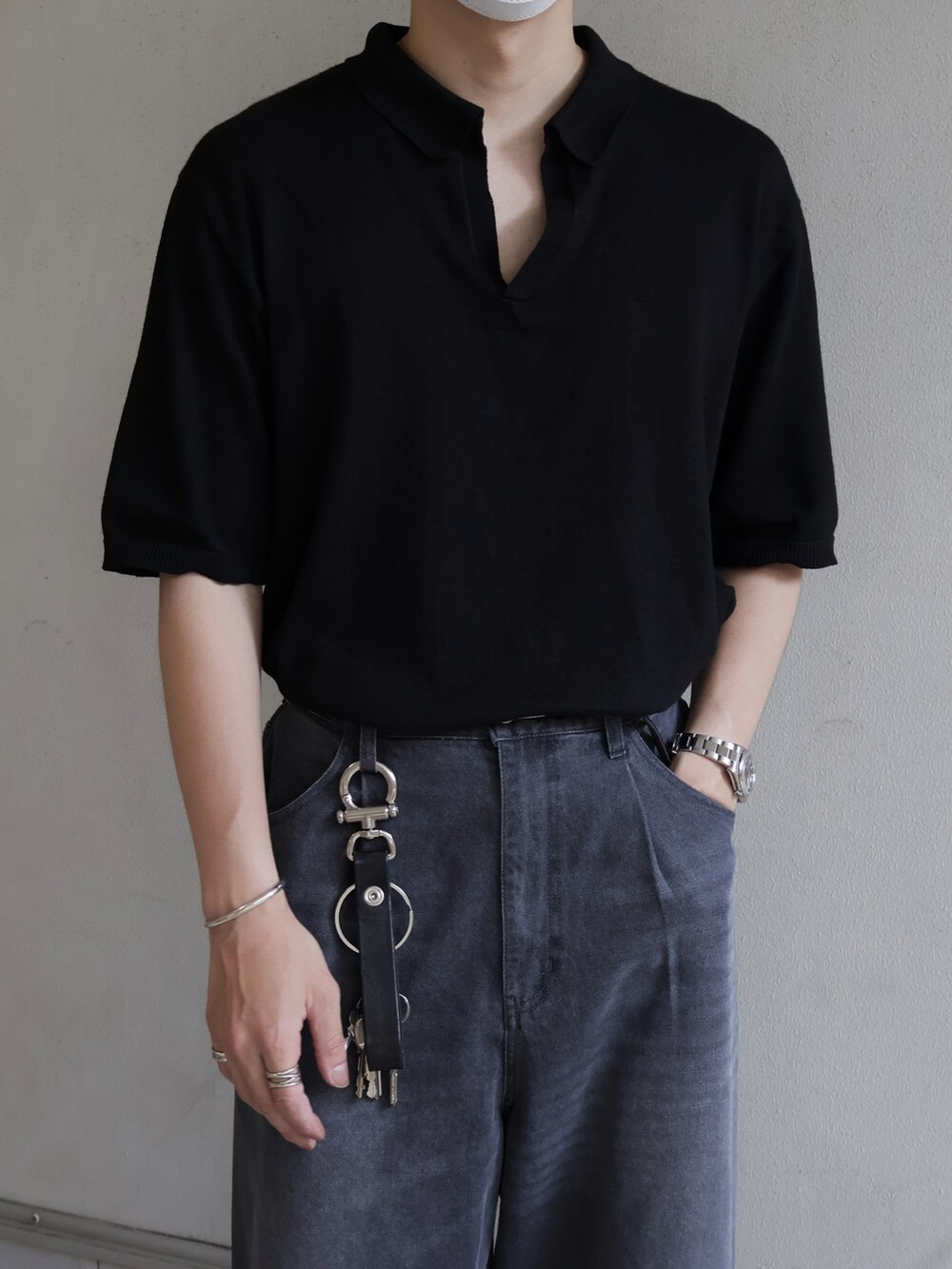 ブラック系のポロシャツ、グレー系のスラックスを着用したメンズの夏コーディネートの2枚目の写真