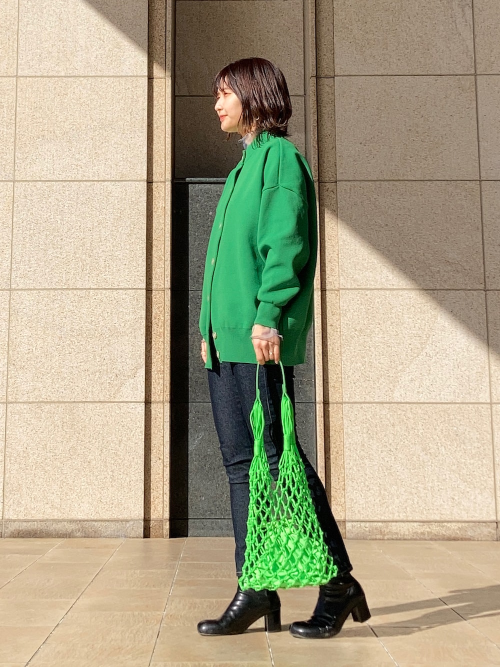 グリーン系のカーディガン/ボレロ、ブルー系のTシャツ/カットソー、グリーン系のトートバッグを着用したレディースの冬コーディネートの2枚目の写真