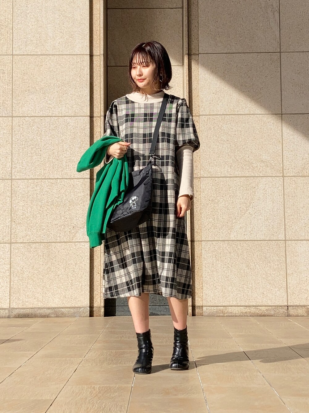 ホワイト系のワンピース、グリーン系のカーディガン/ボレロ、ブラック系のブーツを着用したレディースの冬コーディネートの2枚目の写真