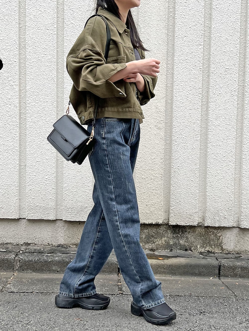 グリーン系のブルゾン、グレー系のキャミソール、ブルー系のデニムパンツを着用したレディースの春コーディネートの2枚目の写真