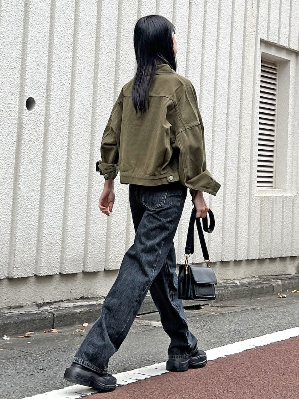 グリーン系のブルゾン、グレー系のキャミソール、ブルー系のデニムパンツを着用したレディースの春コーディネートの3枚目の写真