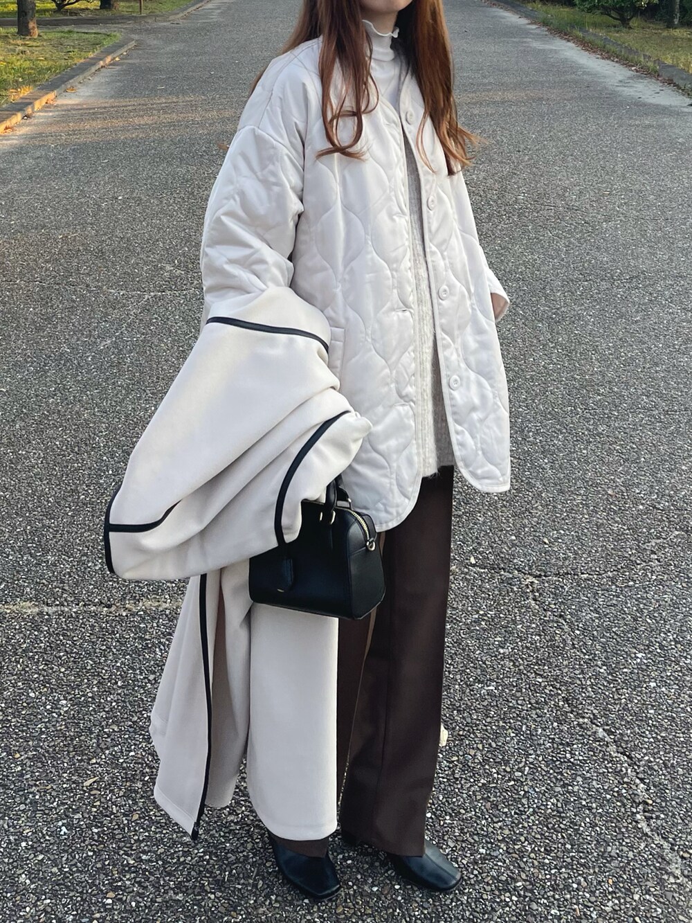 ホワイト系のノーカラーコート、ホワイト系のニット/セーター、ホワイト系のTシャツ/カットソーを着用したレディースの秋コーディネートの3枚目の写真