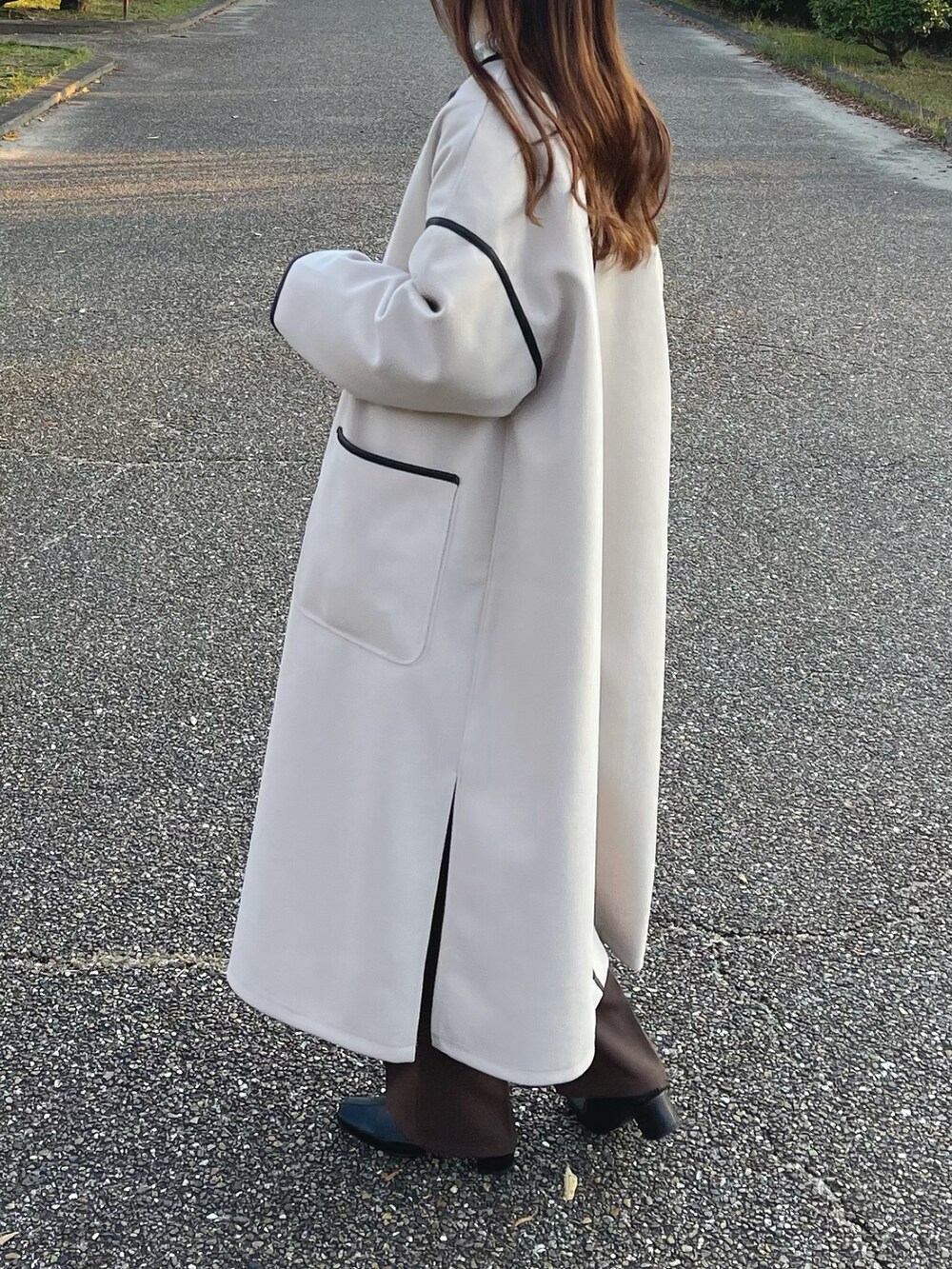 ホワイト系のノーカラーコート、ホワイト系のニット/セーター、ホワイト系のTシャツ/カットソーを着用したレディースの秋コーディネートの2枚目の写真