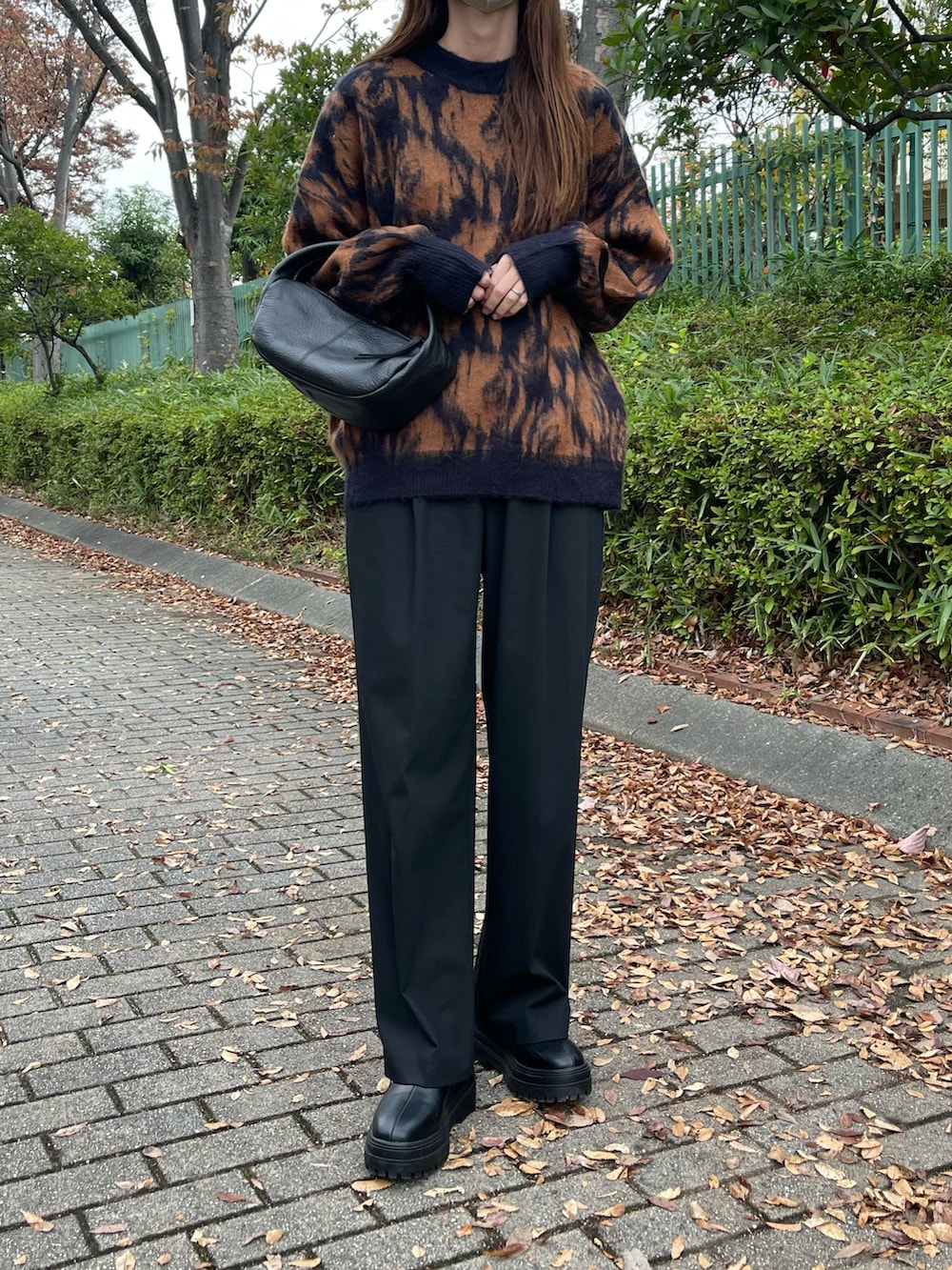 ブラウン系のニット/セーター、ブラック系のパンツ、ブラック系のブーツを着用したレディースの秋コーディネートの2枚目の写真