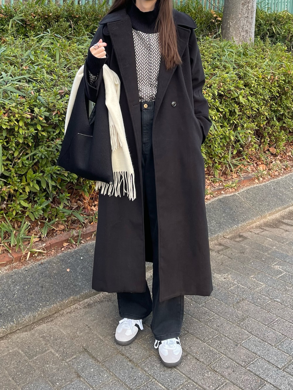 ブラック系のその他アウター、ホワイト系のニット/セーター、ブラック系のデニムパンツを着用したレディースの冬コーディネートの2枚目の写真