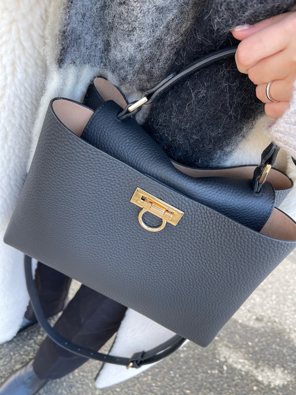 ホワイト系のノーカラーコート、ブラウン系のニット/セーター、ブラック系のスラックスを着用したレディースの冬コーディネートの2枚目の写真