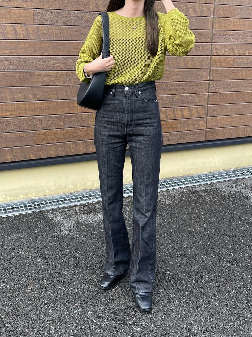 グリーン系のトップス、ブラック系のキャミソール、ブラック系のデニムパンツを着用したレディースの秋コーディネートの3枚目の写真