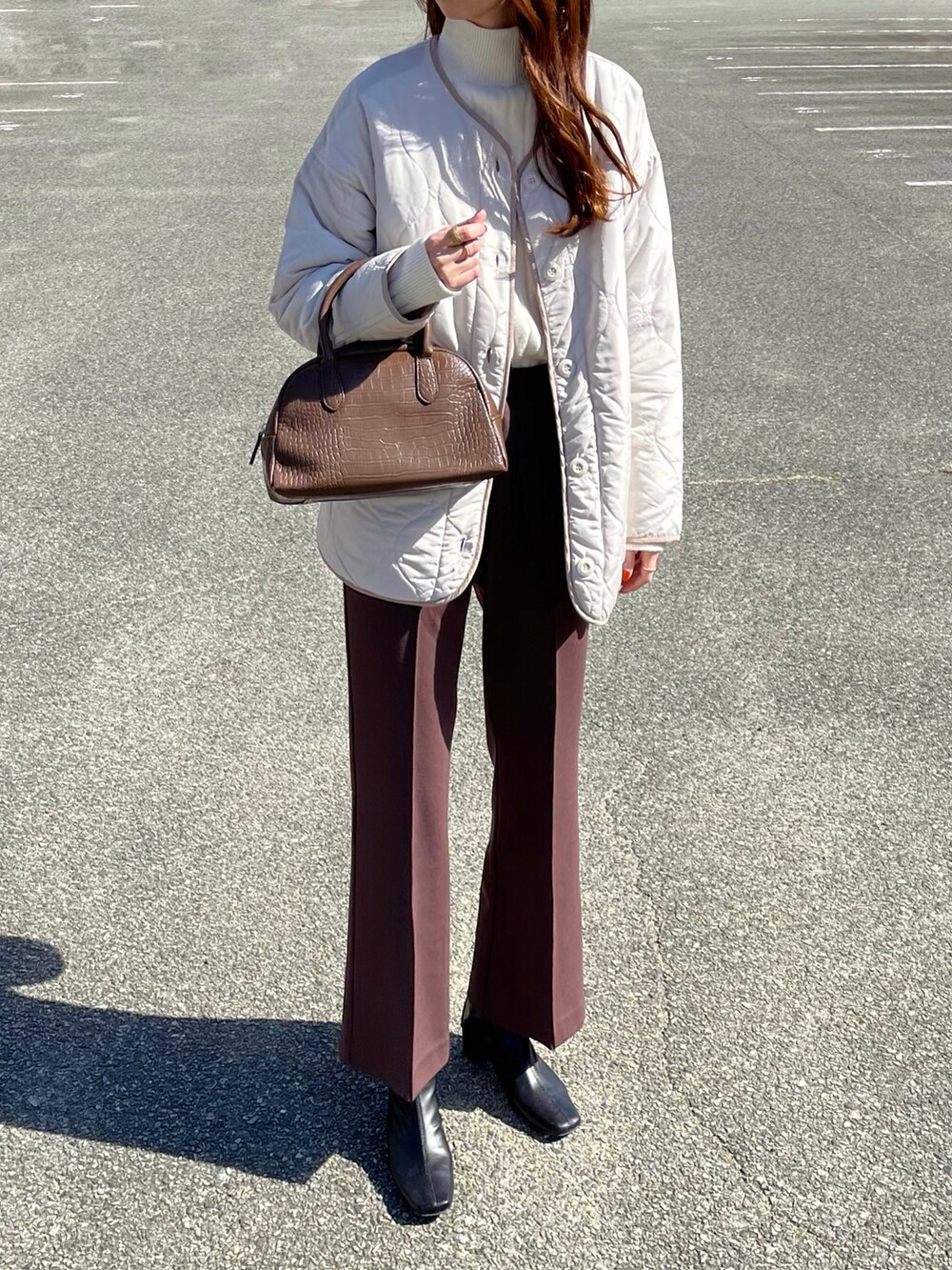 ホワイト系のノーカラージャケット、ホワイト系のニット/セーター、ブラウン系のパンツを着用したレディースの秋コーディネートの2枚目の写真