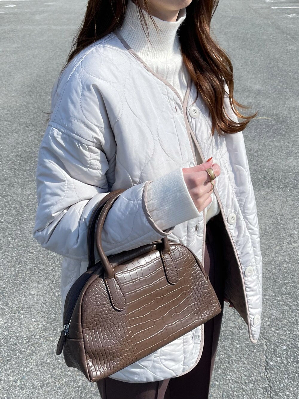 ホワイト系のノーカラージャケット、ホワイト系のニット/セーター、ブラウン系のパンツを着用したレディースの秋コーディネートの3枚目の写真