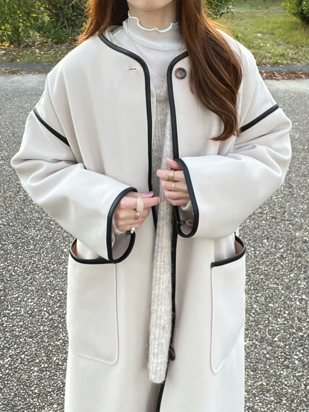 ホワイト系のノーカラーコート、ホワイト系のニット/セーター、ホワイト系のTシャツ/カットソーを着用したレディースの秋コーディネートの4枚目の写真