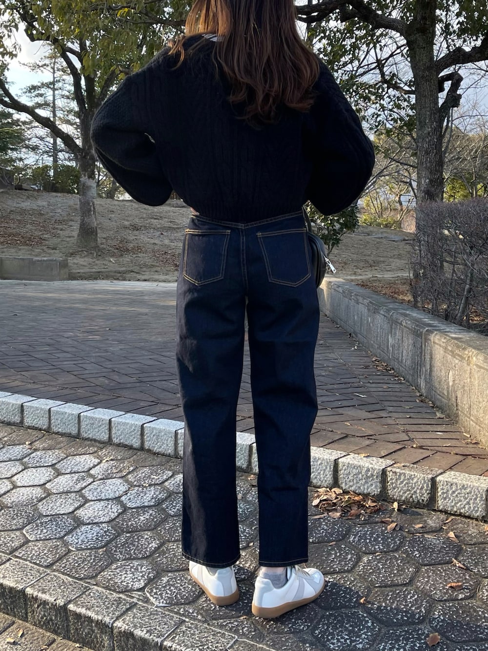 ホワイト系のTシャツ/カットソー、ブラック系のカーディガン/ボレロ、ブルー系のデニムパンツを着用したレディースの冬コーディネートの2枚目の写真