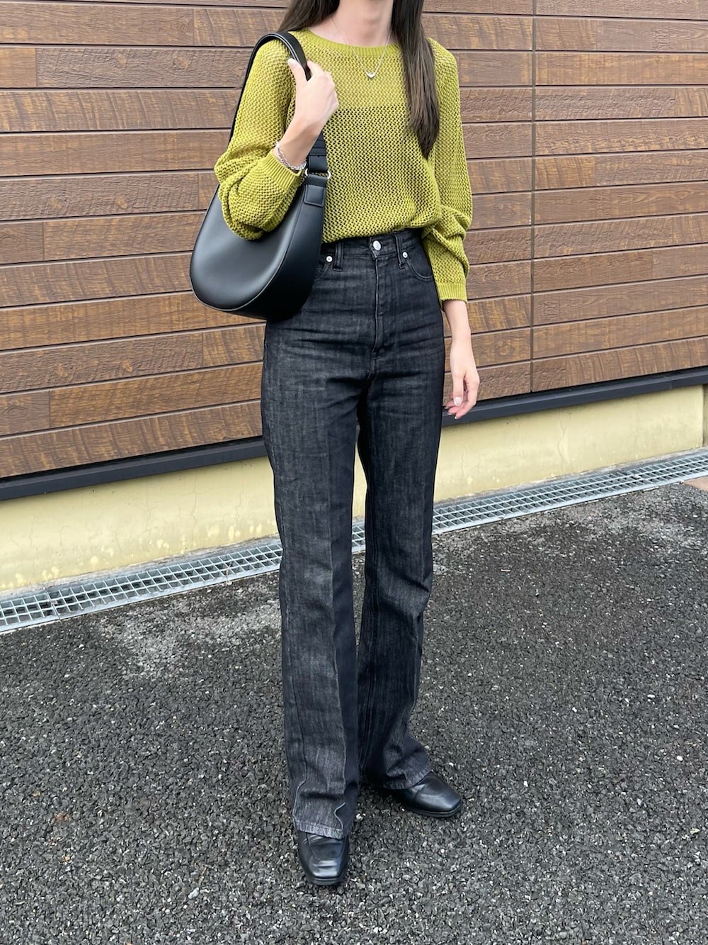 グリーン系のトップス、ブラック系のキャミソール、ブラック系のデニムパンツを着用したレディースの秋コーディネートの2枚目の写真