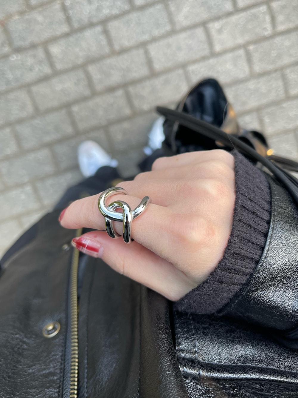 ブラック系のジャケット/アウター、ホワイト系のニット/セーター、ブラック系のデニムパンツを着用したレディースの冬コーディネートの2枚目の写真