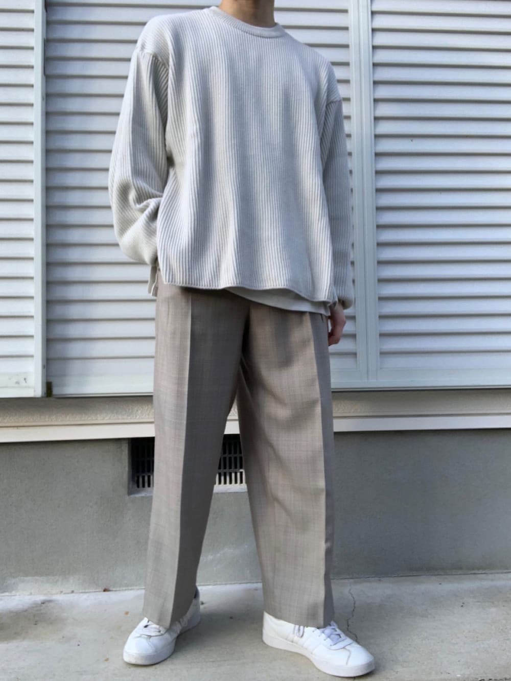 ホワイト系のニット/セーター、ホワイト系のタンクトップ、ベージュ系のスラックスを着用したメンズの冬コーディネートの2枚目の写真