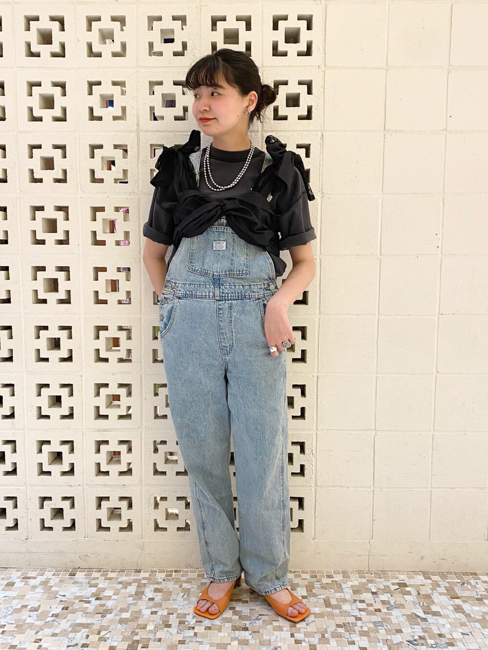 オレンジ系のサンダル、ブルー系のサロペット/オーバーオール、ブラック系のその他トップスを着用したレディースの春コーディネートの2枚目の写真