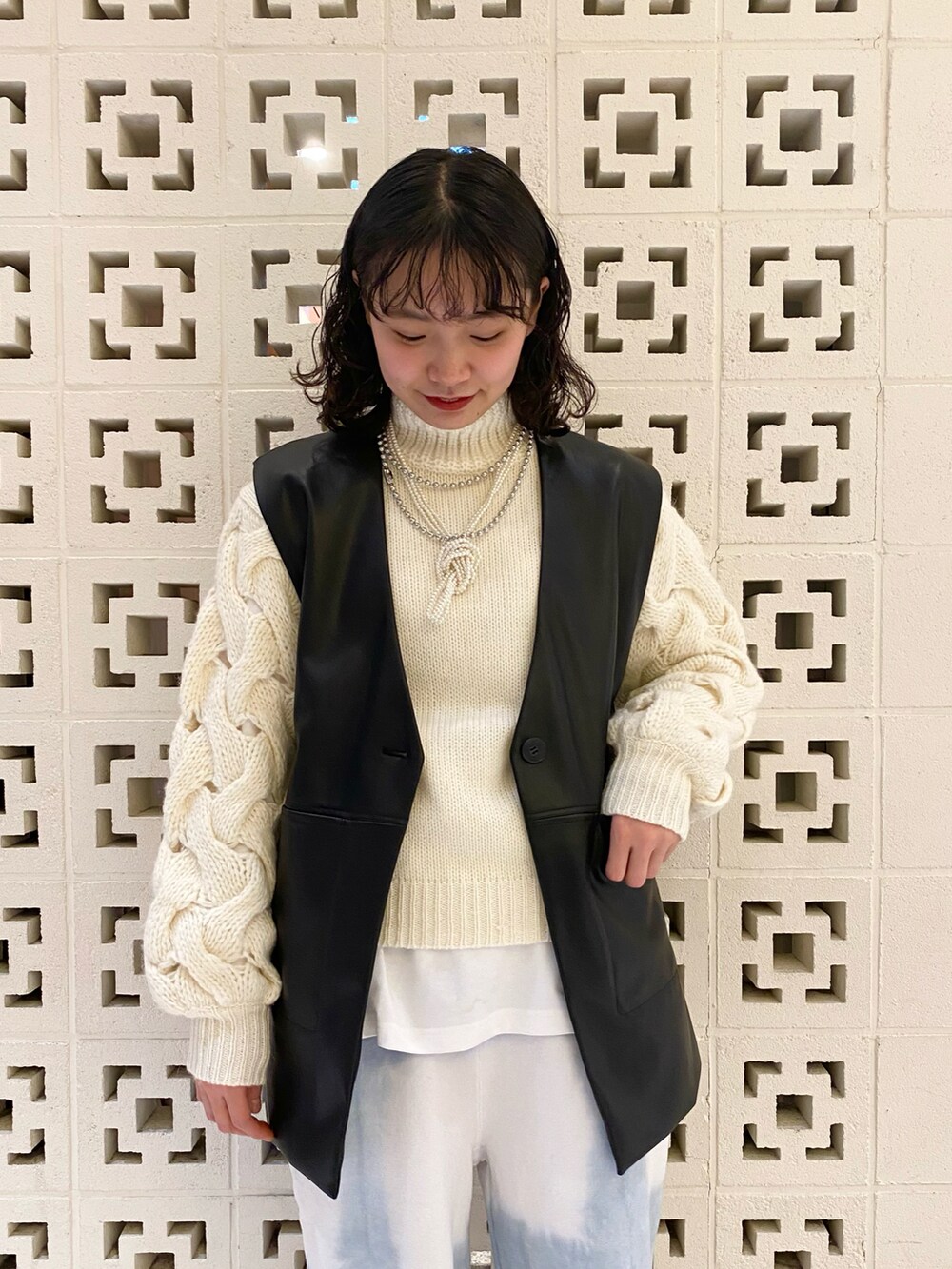 ブラック系のブーツ、レッド系のボストンバッグ、ブルー系のパンツを着用したレディースの冬コーディネートの3枚目の写真