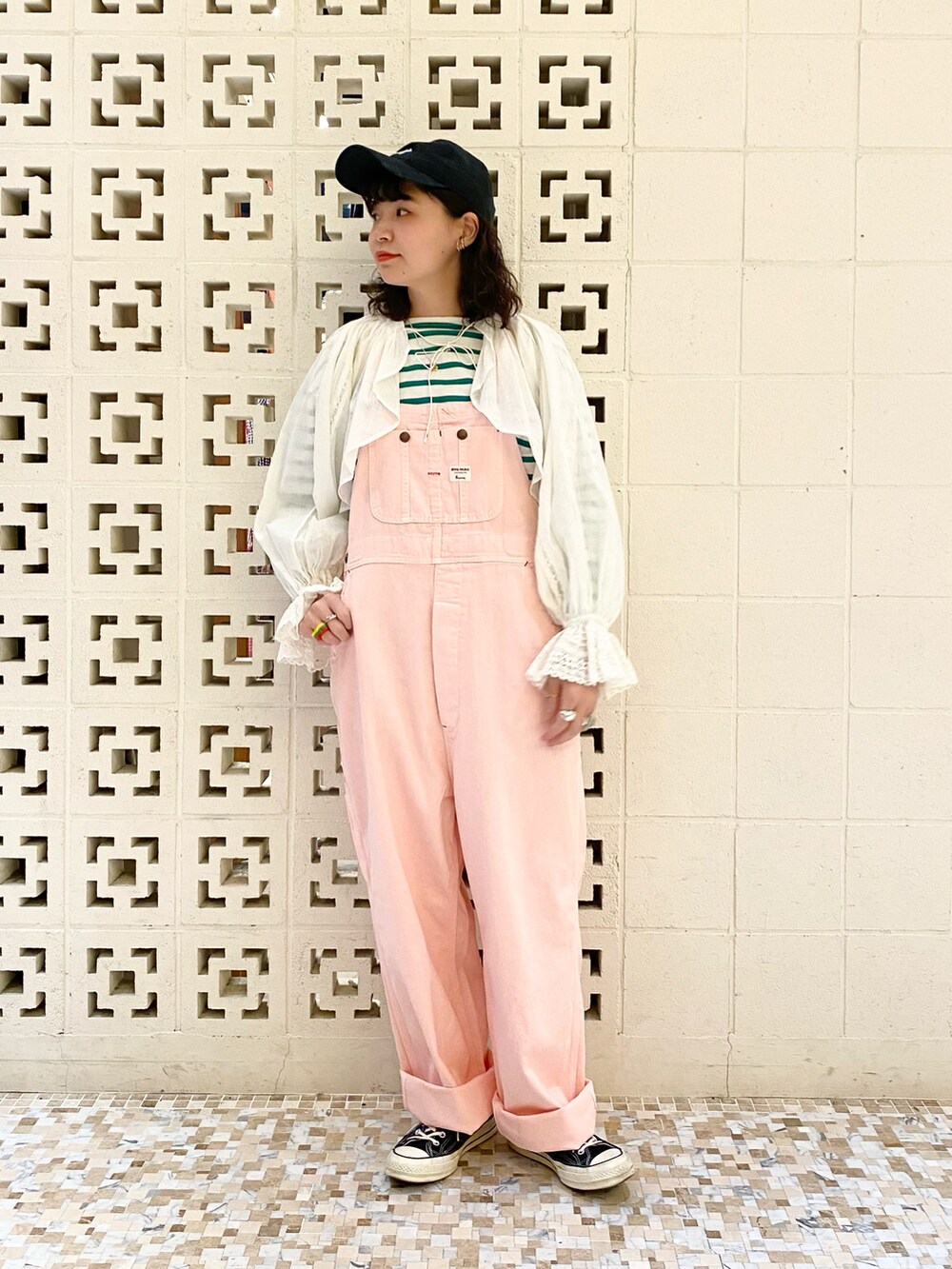 ブラック系のスニーカー、ピンク系のサロペット/オーバーオール、ホワイト系のTシャツ/カットソーを着用したレディースの冬コーディネートの2枚目の写真