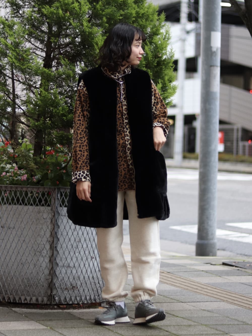 グリーン系のスニーカー、ホワイト系のパンツ、ブラック系のベストを着用したレディースの冬コーディネートの2枚目の写真