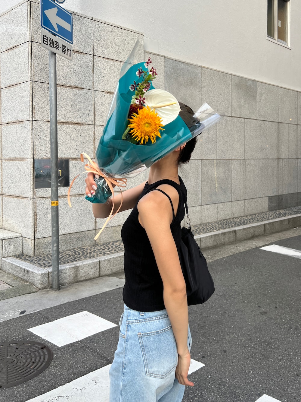 ブラック系のタンクトップ、ブルー系のデニムパンツ、グリーン系のサンダルを着用したレディースの夏コーディネートの3枚目の写真