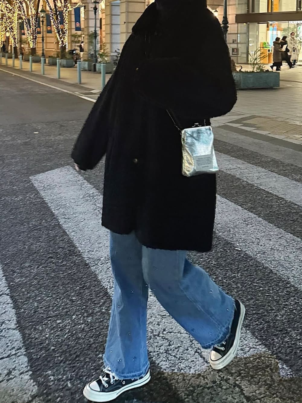 ブラック系のムートンコート、シルバー系のショルダーバッグ、ブルー系のデニムパンツを着用したレディースの冬コーディネートの5枚目の写真