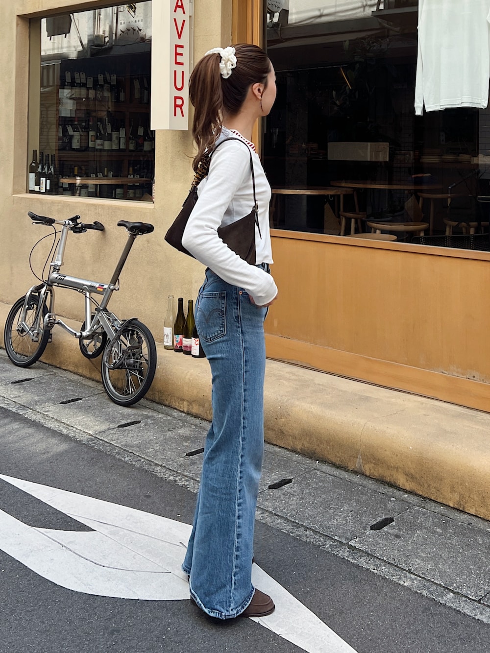 ホワイト系のカーディガン/ボレロ、レッド系のTシャツ/カットソー、ブルー系のデニムパンツを着用したレディースの春コーディネートの2枚目の写真