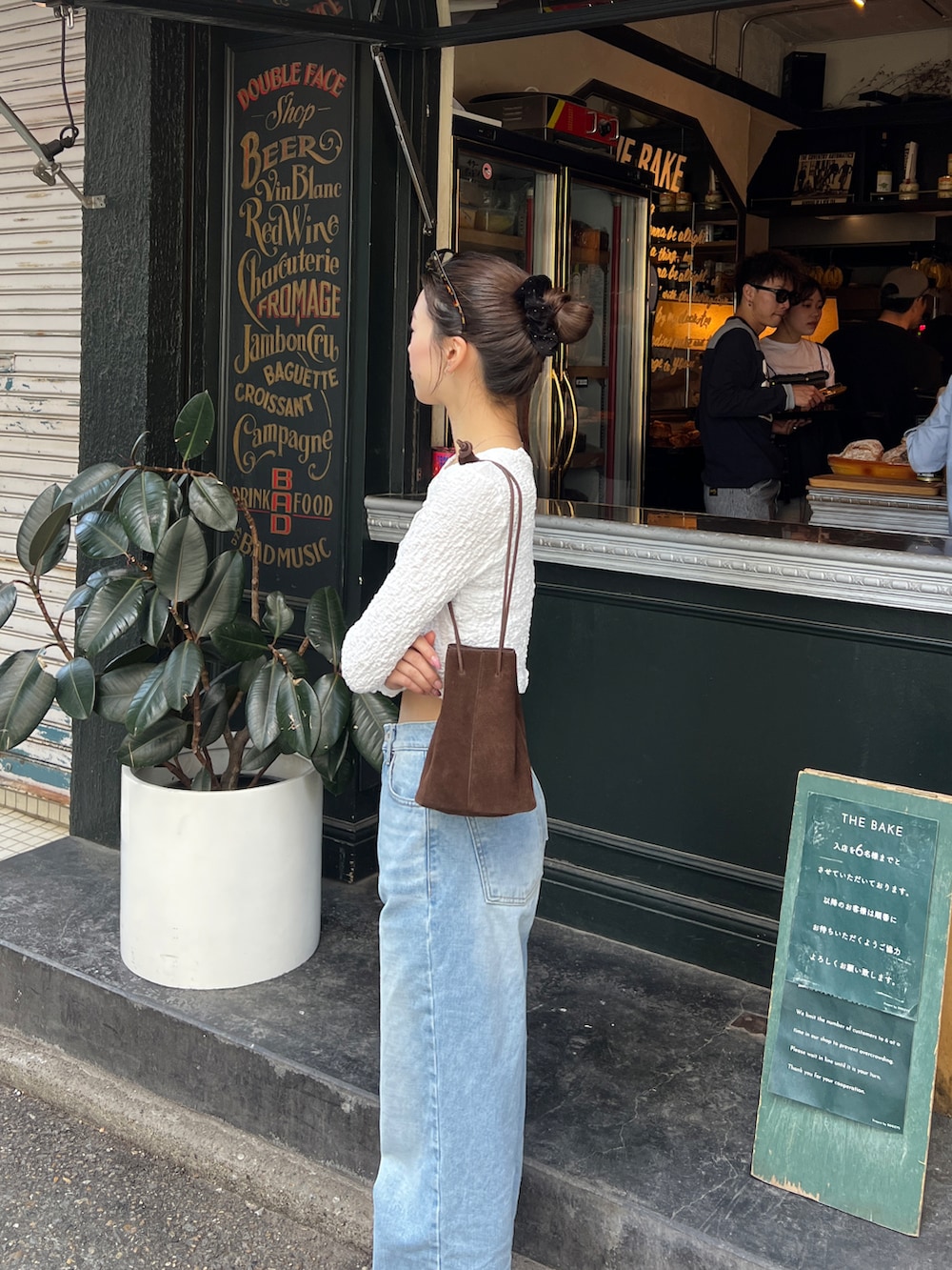 ホワイト系のカーディガン/ボレロ、ブルー系のデニムパンツ、ブラウン系のハンドバッグを着用したレディースの春コーディネートの4枚目の写真