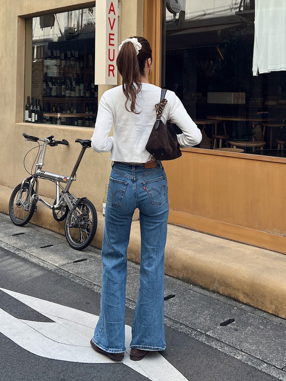 ホワイト系のカーディガン/ボレロ、レッド系のTシャツ/カットソー、ブルー系のデニムパンツを着用したレディースの春コーディネートの3枚目の写真